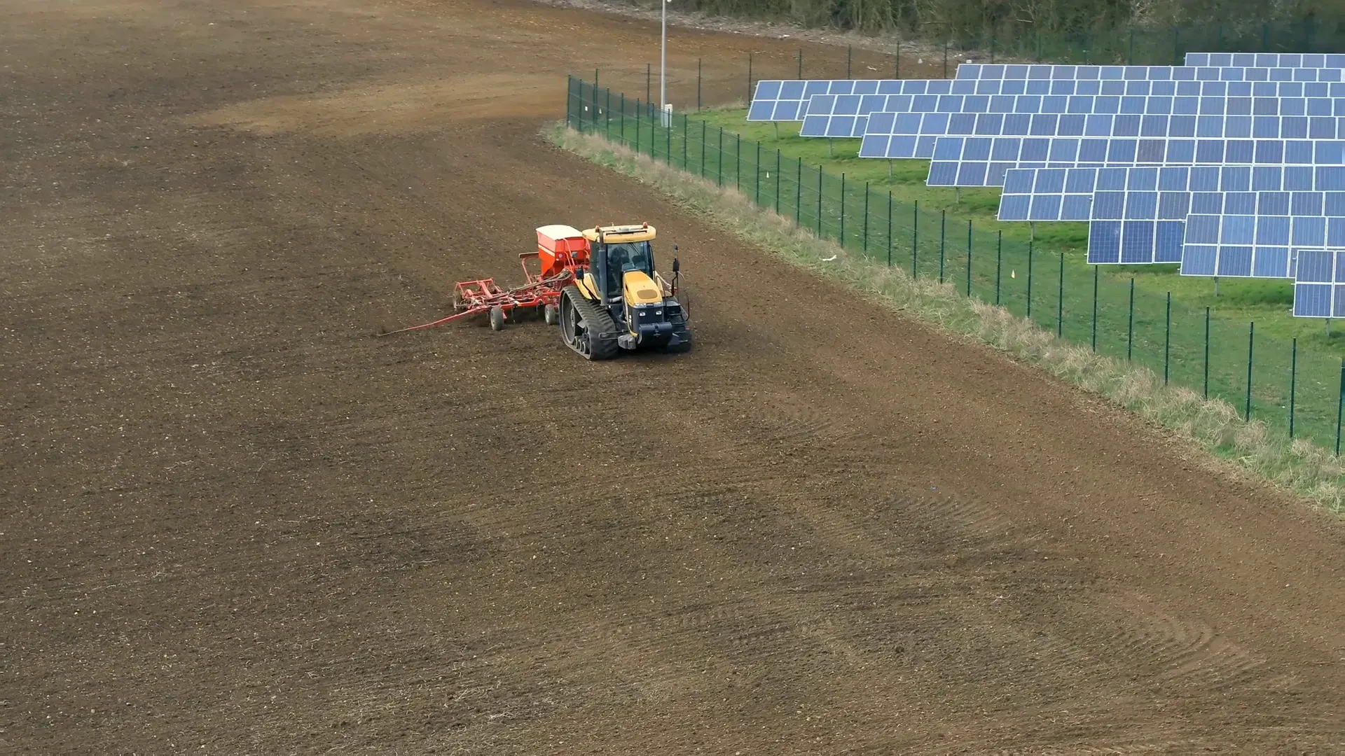 Seeding farmland, Azerbaijan | Karobar Gateways An aerial view of a tractor seeding a large ploughed field beside a line of solar panels